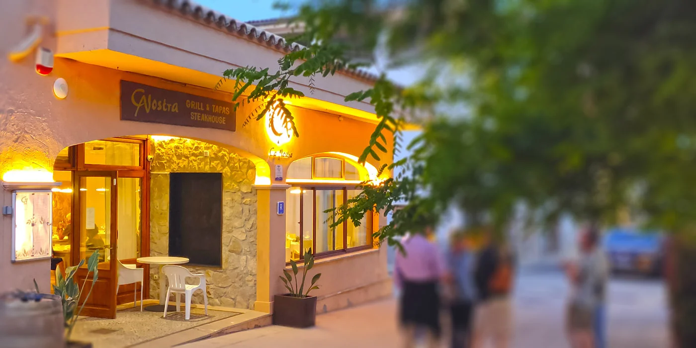 Fachada de Restaurante Ca Nostra iluminada al anochecer